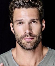 a close up of a person wearing a shirt and holding his hand on his chest