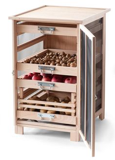 a wooden cabinet with drawers filled with apples and cinnamons on the bottom shelf in front of it