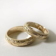 two gold wedding rings sitting next to each other