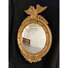 a mirror with an eagle on it is hanging on the wall next to a black curtain