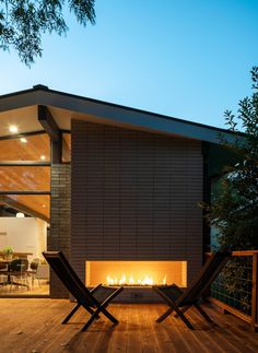 two lounge chairs sitting on top of a wooden deck next to an open fire place