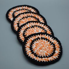 four orange and white coasters sitting on top of a gray table next to each other