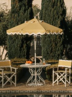 two chairs and an umbrella sitting on the side of a pool