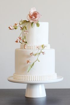 a three layer white cake with pink flowers on top