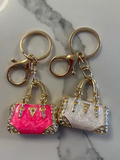 two purse keychains sitting on top of a marble counter