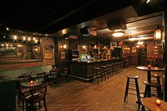 a dimly lit bar with wooden tables and chairs