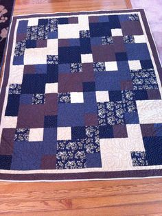 a blue and brown quilt sitting on top of a wooden floor