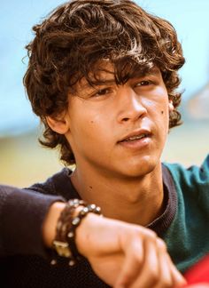 a close up of a person with a watch on his wrist and wearing a sweater