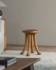 a small wooden stool sitting on top of a rug next to a white couch in a living room