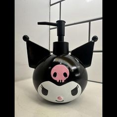 a black and white soap dispenser with a pink skull on the front