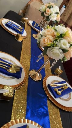 the table is set with blue and gold plates, silverware, and white flowers