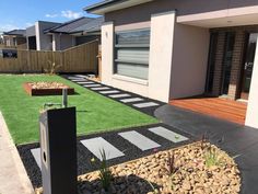 a house with artificial grass in the front yard and landscaping on the other side of the house