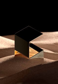 a black and gold object sitting on top of a sandy surface in the sun light