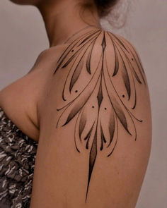 the back of a woman's shoulder with an intricate tattoo design on her arm