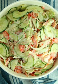 a bowl filled with cucumbers and carrots on top of a blue towel