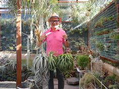 a man in a pink shirt is holding up some plants