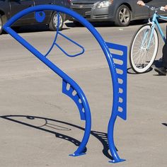 a person riding a bike next to a blue bicycle rack on the side of a road