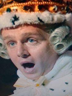 a man with a crown on his head making a surprised face