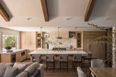 an open kitchen and living room area with couches, chairs, table and cabinets