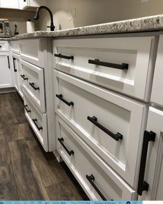 a kitchen with white cabinets and black handles on the doors, counter tops and drawers