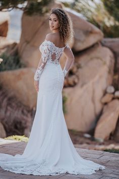 a woman in a white wedding dress standing near rocks