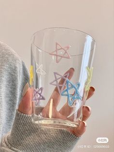 a person holding a glass with different colored stars on it