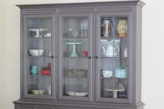 a gray china cabinet with glass doors and shelves