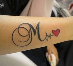 a woman's arm with a tattoo on it that reads mom and has a heart