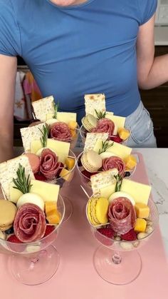 two wine glasses filled with different types of cheese and crackers on top of a table