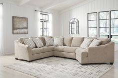 a living room with a large sectional couch and rug in front of the window on the floor