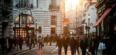 a group of people walking down a street next to tall buildings with traffic lights on them