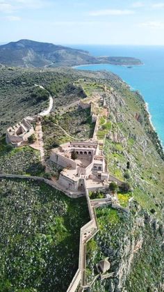 an aerial view of a castle on the side of a hill next to the ocean