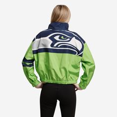 a woman wearing a green and blue jacket with the seattle football team on it's back