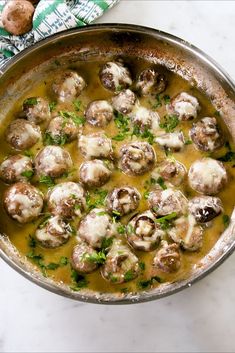 a pan filled with meatballs covered in gravy and garnished with parsley