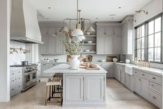 a large kitchen with gray cabinets and white counter tops, an island in the middle