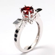 This dark and beautiful engagement ring is made with a gorgeous 1ct blood red natural garnet. Is accented by natural black sapphire and features a stunning skull with bat wings. Can be made in your choice of 925 sterling silver or 14k white gold. Can be made in yellow or rose gold upon request. Gothic Ruby Promise Ring, Gothic Halloween Skull Ring, Gothic Red Ruby Promise Ring, Elegant Red Skull Ring For Anniversary, Elegant Red Skull Ring For Wedding, Skull Vampire, Fantasy Punk, Vampire Horror, Wing Ring