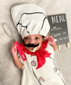 a baby wearing a chef's hat and holding a whisk in it's mouth