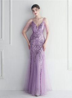 This purple mermaid prom dress is a spectacle of modern elegance, curated for grand prom nights, majestic balls, and formal soirees. The patterned sequins embellished on the mesh v-neck bodice sparkle as they catch light, supported gracefully by spaghetti straps. The zipper-up back ensures a flattering fit, while the tassel cap sleeves add a touch of playful sophistication. The beading adornments are a nod to meticulous craftsmanship, adding layers of luxury. The tulle skirt glides over the hips, elegantly making its way to the floor, showcasing a silhouette that is nothing short of glamorous. Purple Mermaid Prom Dress, Purple Tulle, Tulle Tutu Dress, Mermaid Maxi Dress, Beaded Mermaid, Beaded Party Dress, Fishtail Maxi Dress, Dresses Birthday, Glitter Mermaid