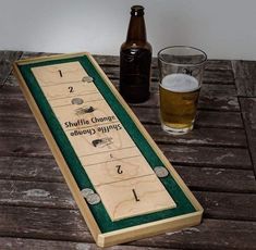 a wooden shuffle board next to a glass of beer on a table with two bottles