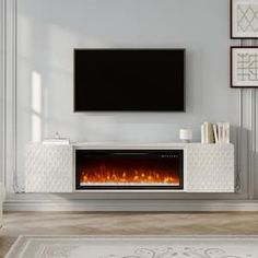 a living room with a fireplace and tv on the wall in front of two framed pictures