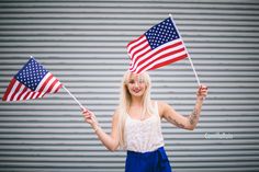 a woman holding two american flags in her hands