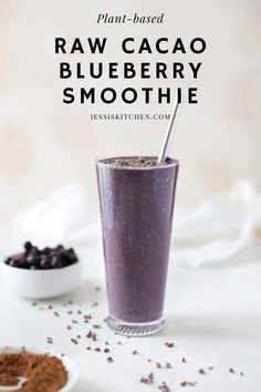 a glass filled with blueberry smoothie next to a spoon