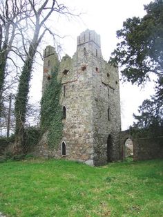 an old stone building sitting on top of a lush green field next to tall trees