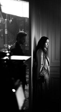 black and white photograph of man and woman standing in front of door looking at each other