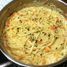 a pan filled with pasta and carrots on top of a stove