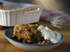 a bowl filled with food sitting on top of a wooden table next to another bowl