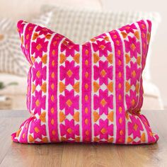 a pink and orange pillow sitting on top of a wooden table