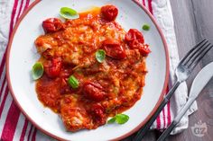 a white plate topped with meat covered in tomato sauce