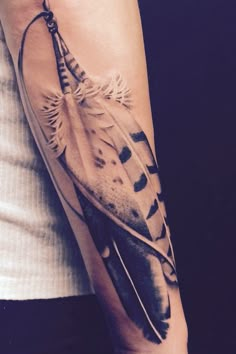 a woman's arm with a feather tattoo on it