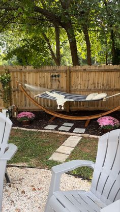 two lawn chairs sitting next to each other in front of a wooden fence with a hammock on it